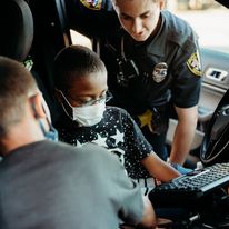 children learning about the inside of a police car with an officer
