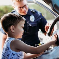 young child honking the horn of a police car
